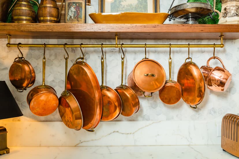 Copper pots hanging above a white marble kitchen countertop.